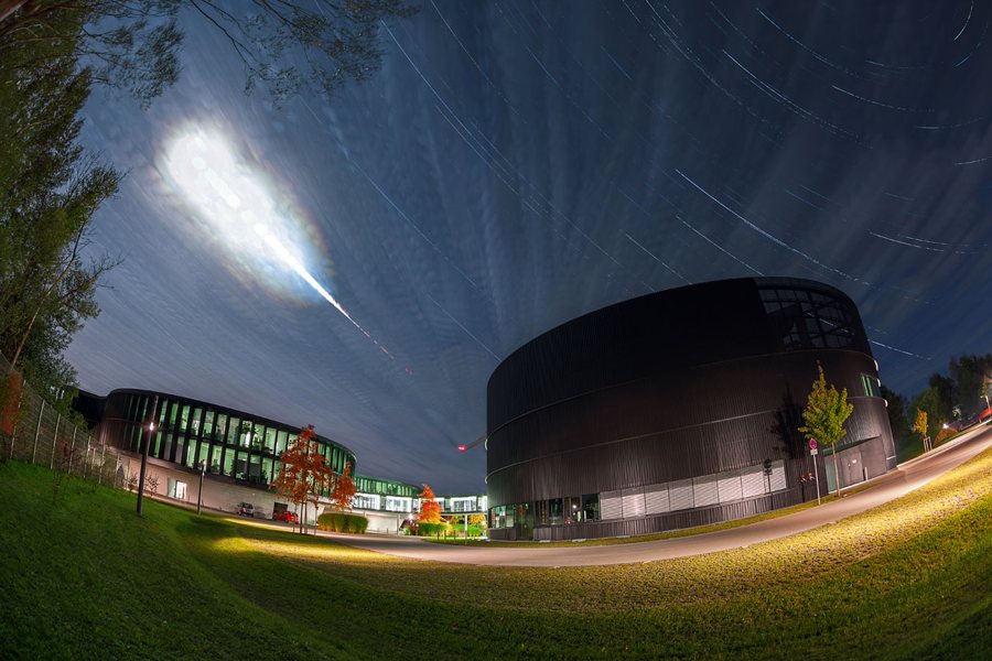 A reddish totally eclipsed Moon above a building at night